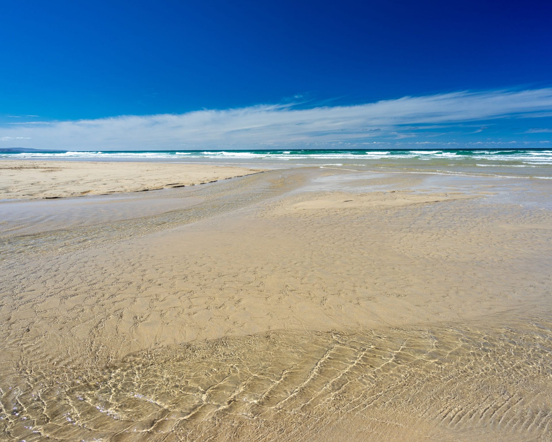 Une plage avec un ciel dégagé et des vagues calmes.