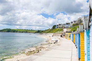 A coastal promenade with a row of colorful buildings, a sandy beach, and a clear view of the sea. - Ocean Waves Apartment - sleeps 4 guests  in 2 bedrooms (Falmouth)