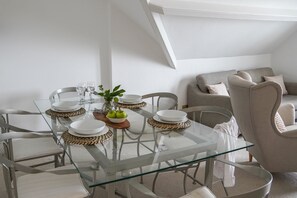 A dining area with a glass table, woven placemats, and a vase with green apples. - Ocean Waves Apartment - sleeps 4 guests  in 2 bedrooms (Falmouth)