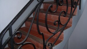 A staircase with ornate black metal railings and red-tiled steps. - Bijou un havre de paix   dans un immeuble de caractére du patrimoine historique (Montauban)
