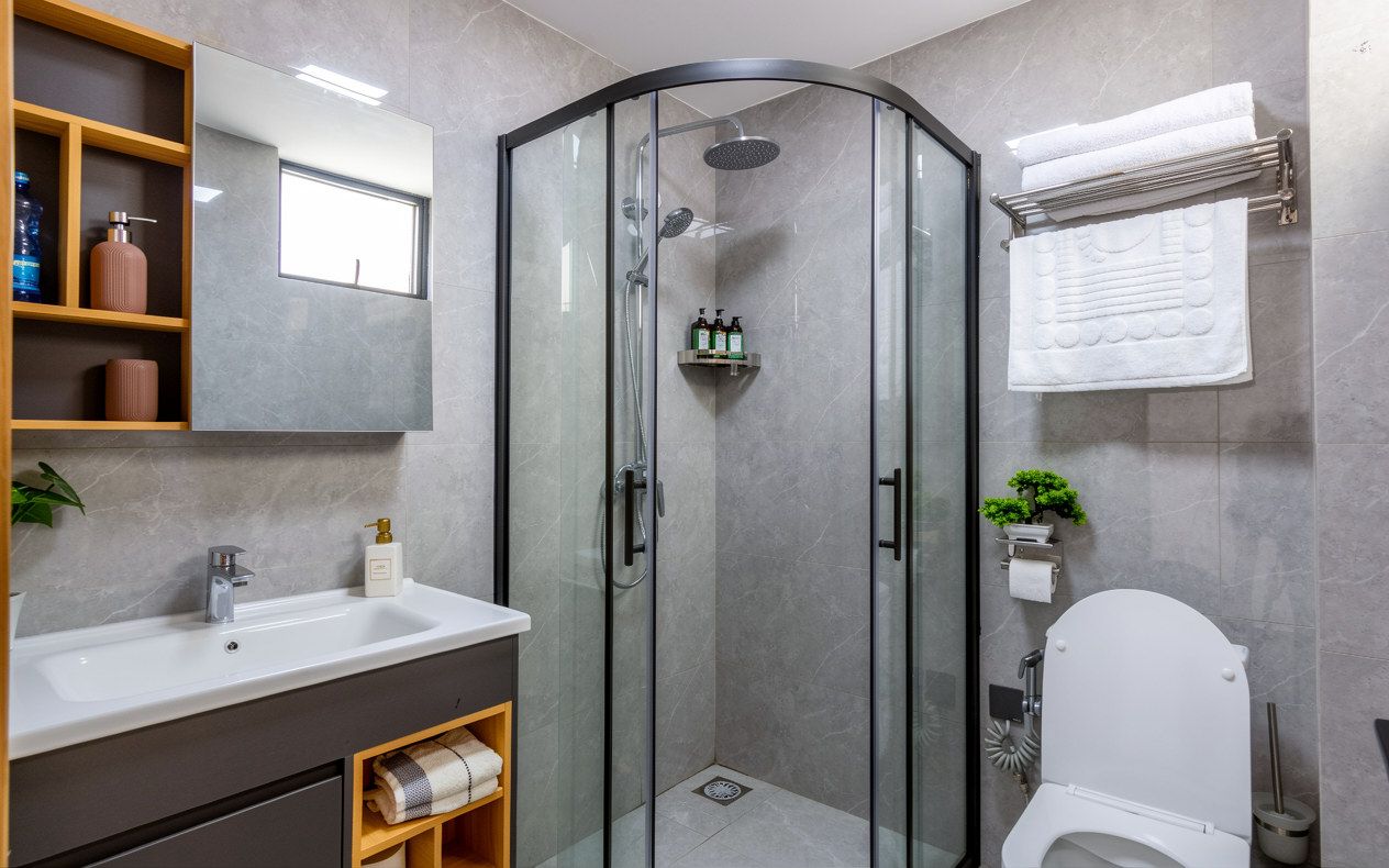 A modern bathroom with a glass-enclosed shower, a white sink, and a toilet.