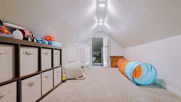Ein Kinderzimmer mit Etagenbett, Stauraumeinheiten und einem Spieltunnel.