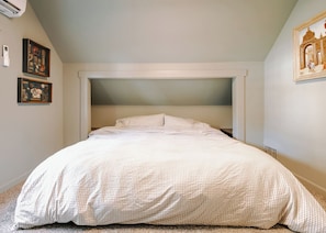 Ein Schlafzimmer mit einem Bett, einer Kopfteil und einer Wand-Klimaanlage.