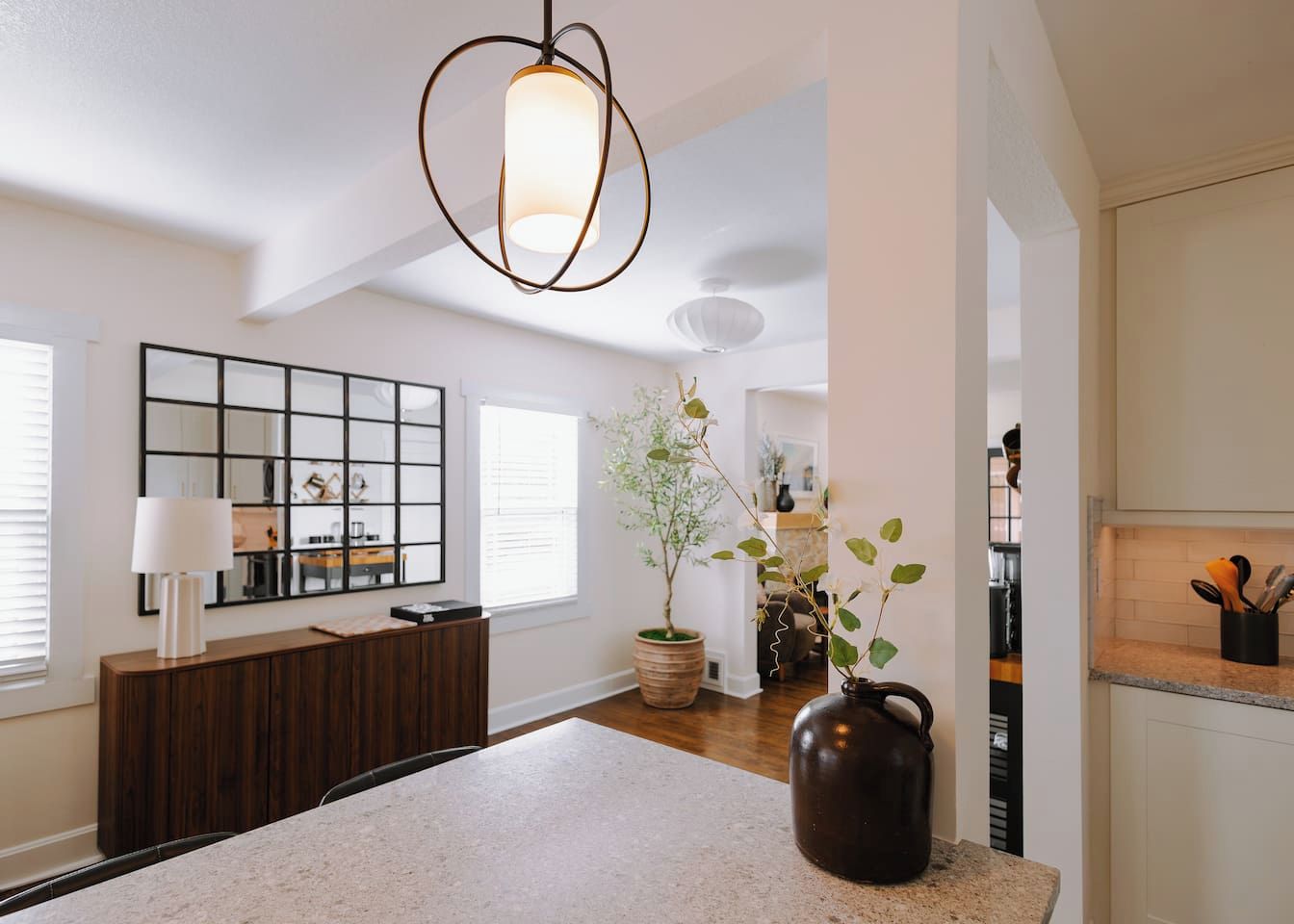 Une cuisine moderne avec un îlot central, un luminaire suspendu, une plante en pot et un meuble en bois.