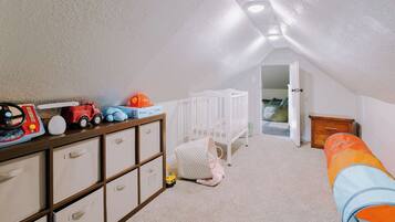 Quarto de brinquedos infantil com berço, unidade de armazenamento e brinquedos.