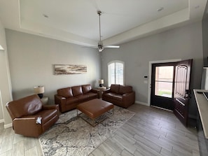 A living room with a sectional sofa, a coffee table, a floor lamp, and a ceiling fan.