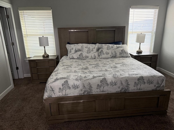 A bedroom with a wooden bed, two bedside tables, a nightstand, and a door.