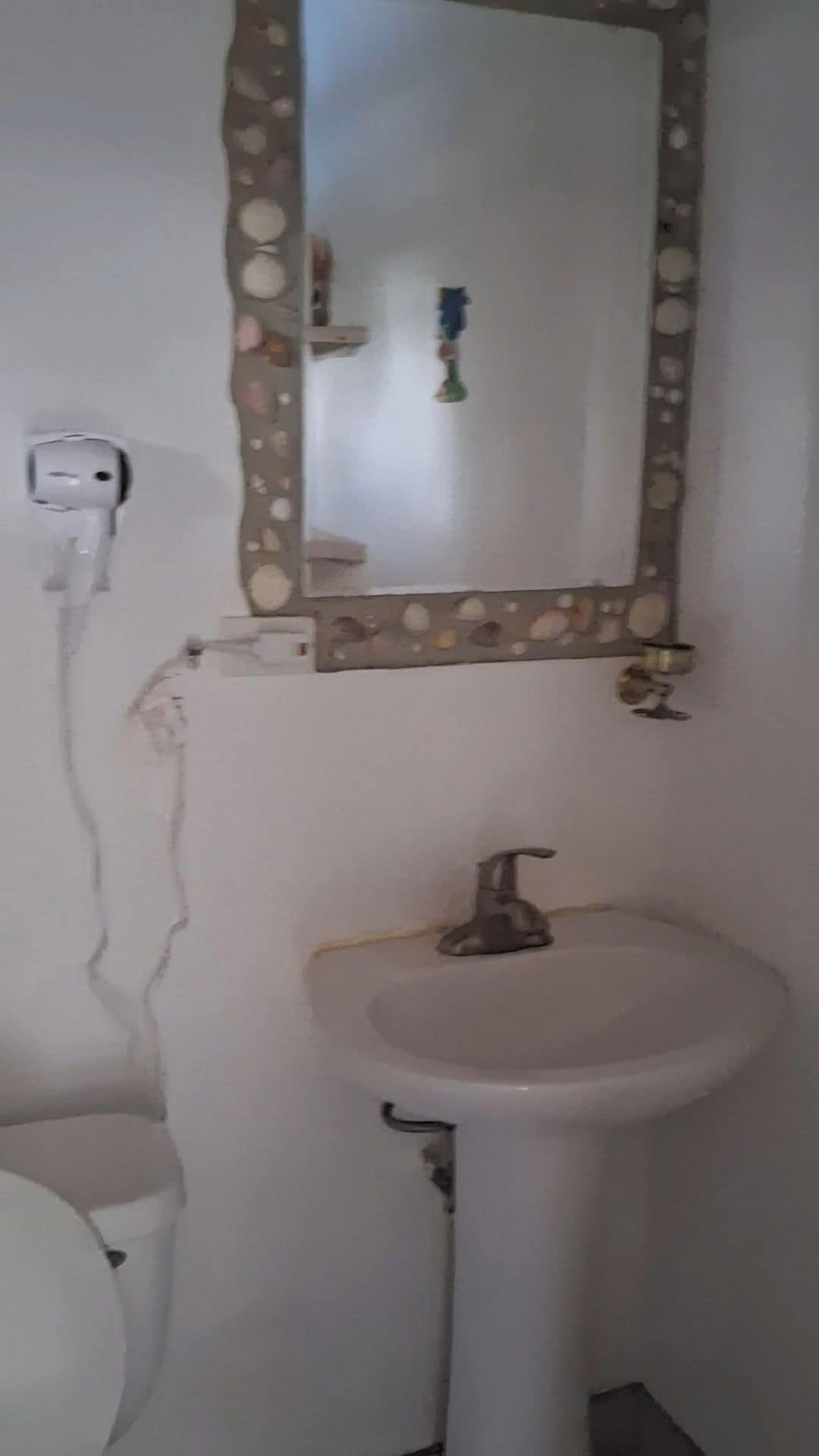 A bathroom with a white sink, a mirror with a decorative frame, and a toilet.