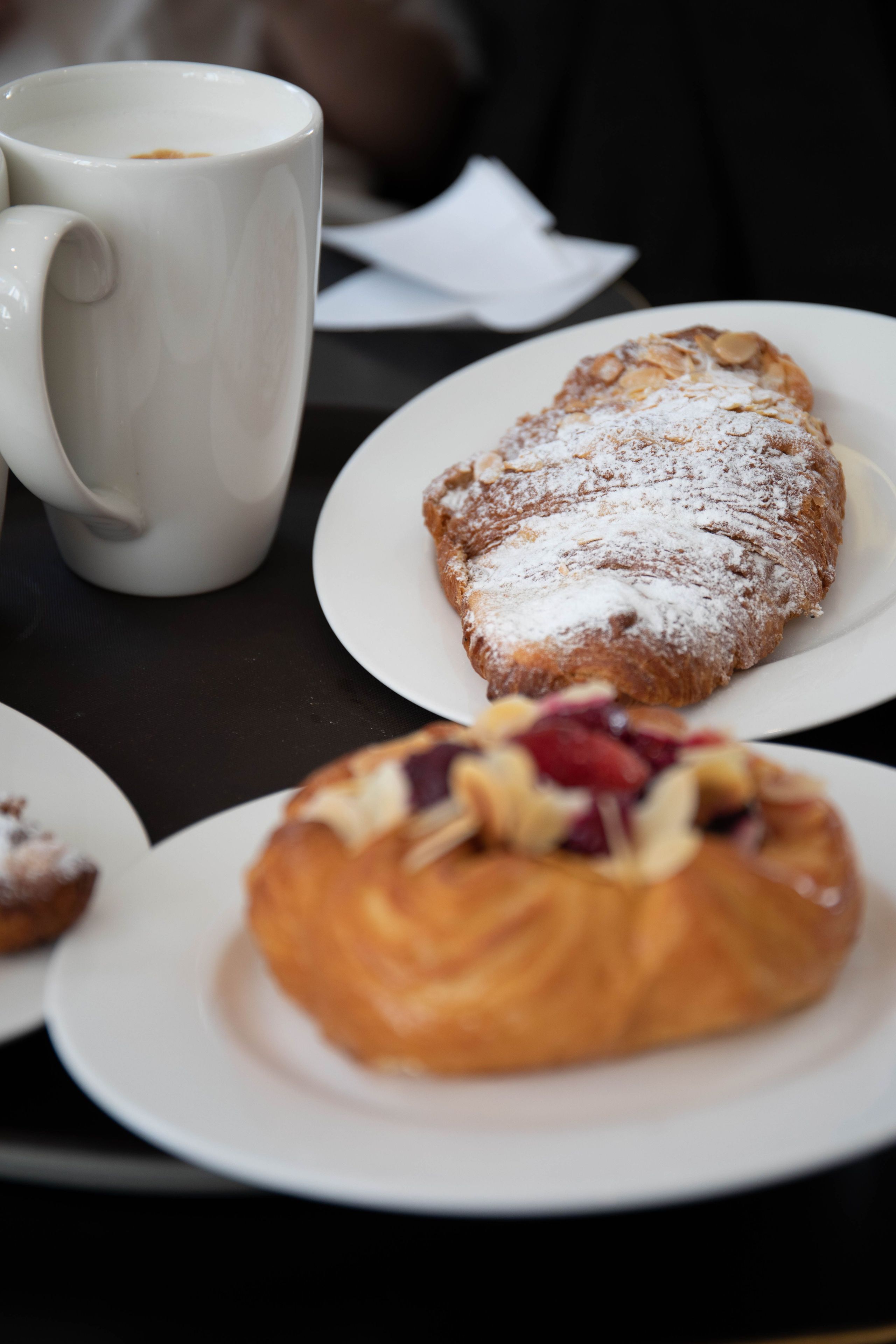 Una mesa con una taza de café blanca y dos platos de pastelería.