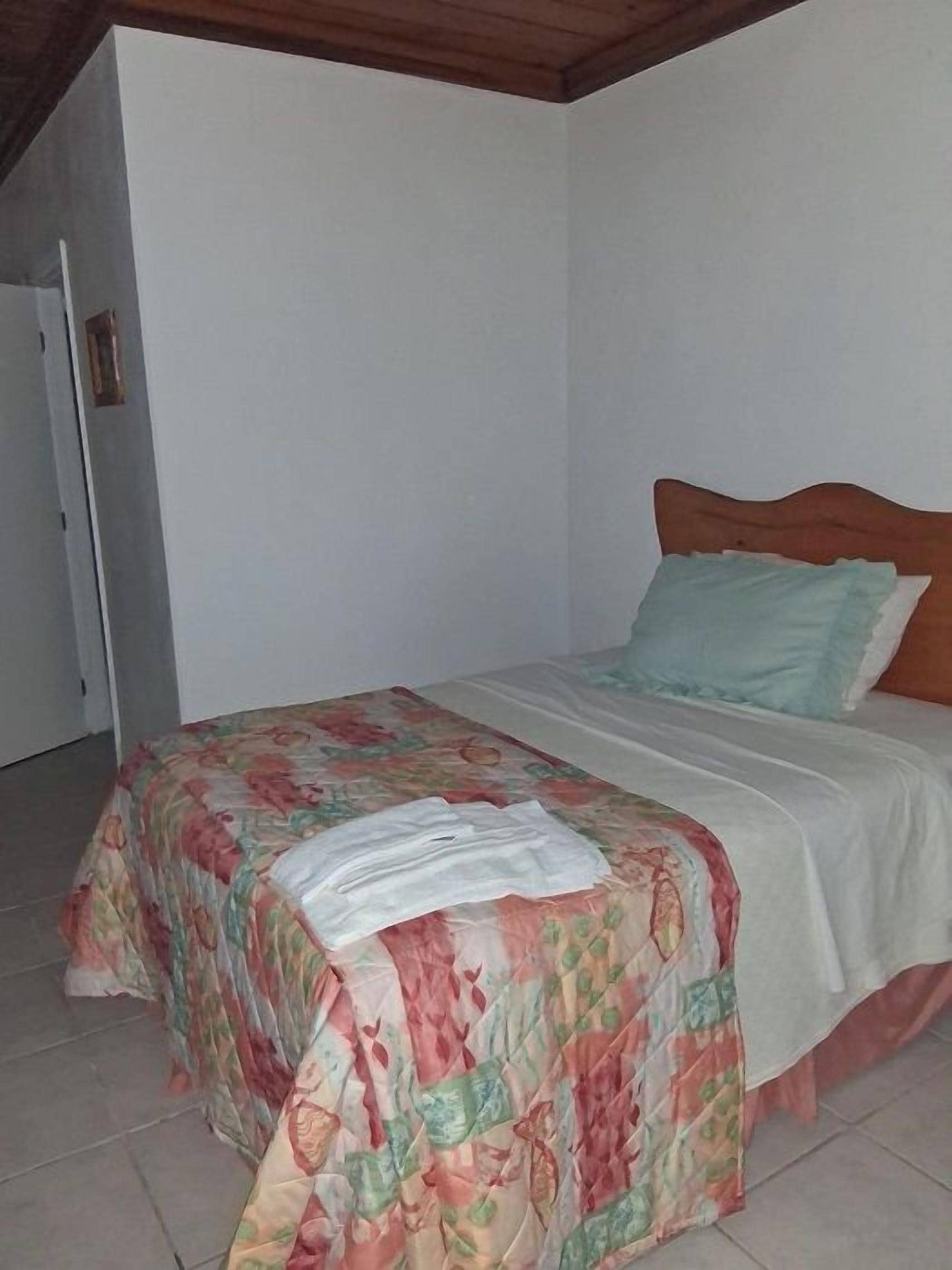 Een slaapkamer met een bed, een houten hoofdbord en een witte muur.