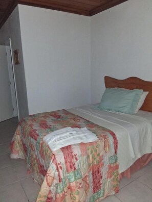 A bedroom with a bed, a wooden headboard, and a white wall.