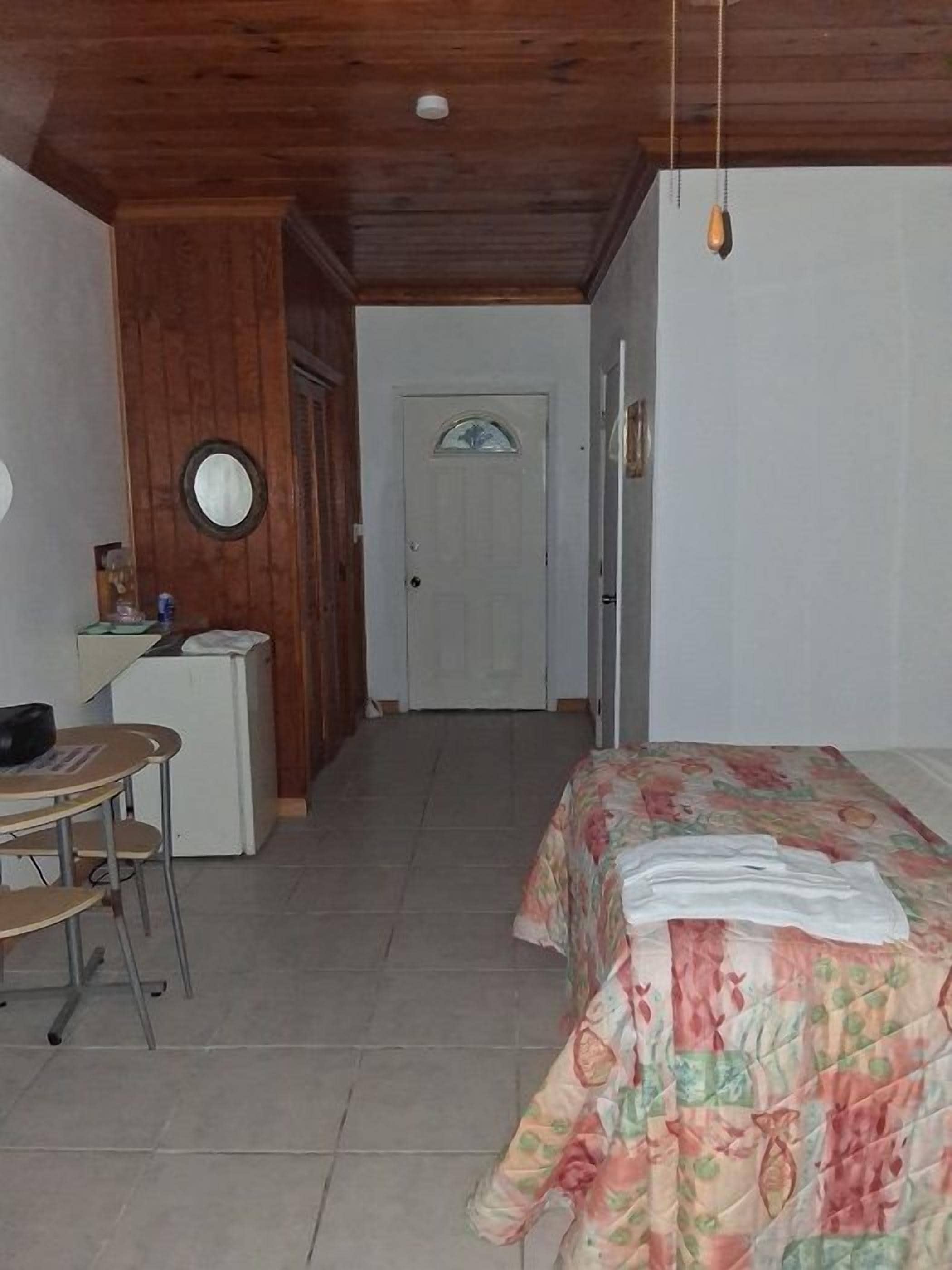 Quarto com cama, escrivaninha e cadeira. Uma porta ao fundo.