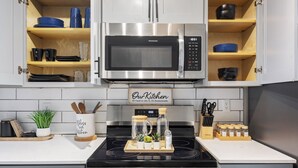 Une cuisine équipée d’une cuisinière en acier inoxydable, d’un four à micro-ondes et de meubles de rangement en bois.