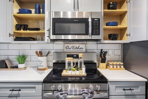 A kitchen with a stainless steel stove, a microwave, and wooden cabinets.