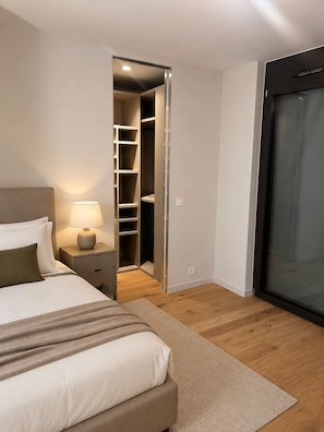 A bedroom with a bed, bedside table, lamp, and a walk-in closet.