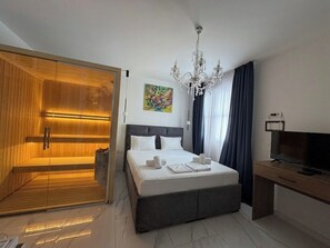 A modern hotel room with a large bed, a television, a wooden wardrobe, and a shower area. - Maison Mark Spa & Suites (Belgrade)