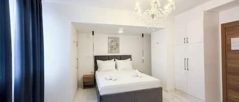 A modern bedroom with a large bed, a chandelier, and a wardrobe.