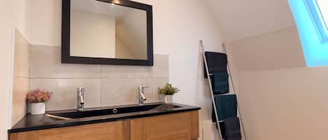 A modern bathroom with a wooden vanity, a large mirror, and a skylight.