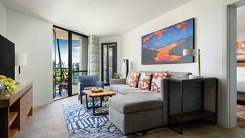 A modern living room with a sofa, a coffee table, and a chair. There is a large window with a view of the outdoors.
