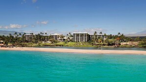 A beachfront hotel with multiple buildings, a sandy beach, and clear turquoise waters.