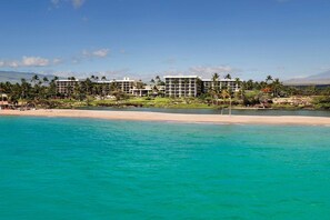 A beachfront hotel with multiple buildings, a sandy beach, and clear turquoise waters.