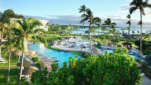 A resort with a large pool, palm trees, and a view of the ocean.