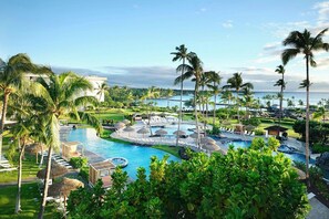 A resort with a large pool, palm trees, and a view of the ocean.