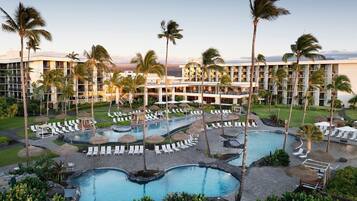 A resort with multiple swimming pools, palm trees, and a large building with balconies.