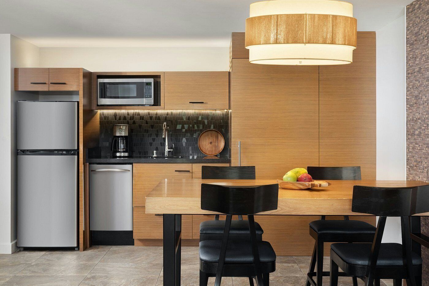 A modern kitchen with a built-in microwave, a coffee maker, and a wooden dining table with chairs.