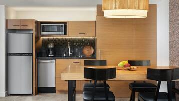 A modern kitchen with a built-in microwave, a coffee maker, and a wooden dining table with chairs.