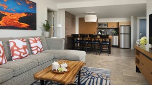 A modern living room with a gray sofa, a wooden coffee table, and a dining area with a kitchen in the background.