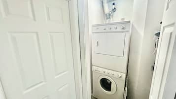 Un cuarto de lavado con lavadora y secadora de carga frontal, un calentador de agua y una puerta.