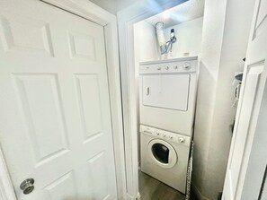 A laundry room with a front-loading washer and dryer, a water heater, and a door.