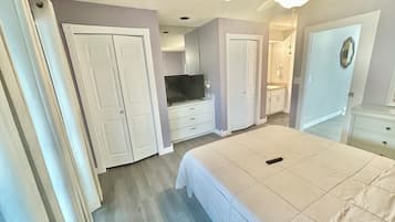 A bedroom with a bed, a television, a wardrobe, and a bathroom.