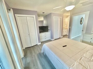 A bedroom with a bed, a television, a wardrobe, and a bathroom.
