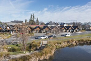Une rangée de bâtiments modernes, avec un parking et une étendue d’eau au premier plan.
