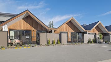 A row of modern, wooden-framed buildings with large windows and a gated entrance.
