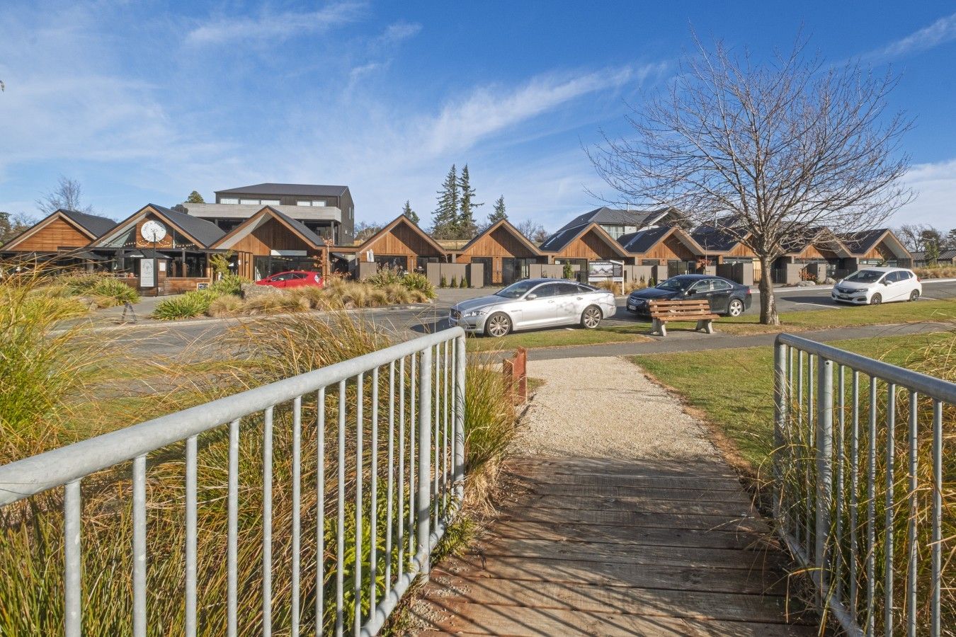 A pathway leading to a row of modern, wooden cabins with a car parked nearby.