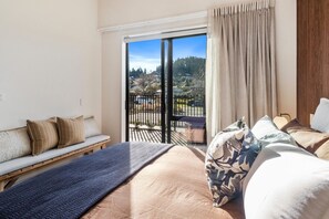 Une chambre d’hôtel avec un lit, un banc et une vue sur un balcon doté d’une balustrade.