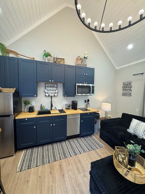 A compact kitchen with dark blue cabinets, a microwave, and a wooden countertop.