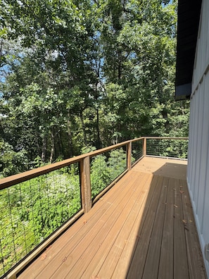 A wooden deck with a metal railing overlooking a dense forest.