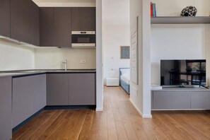 Una cocina moderna con armarios grises, horno empotrado y piso de madera.