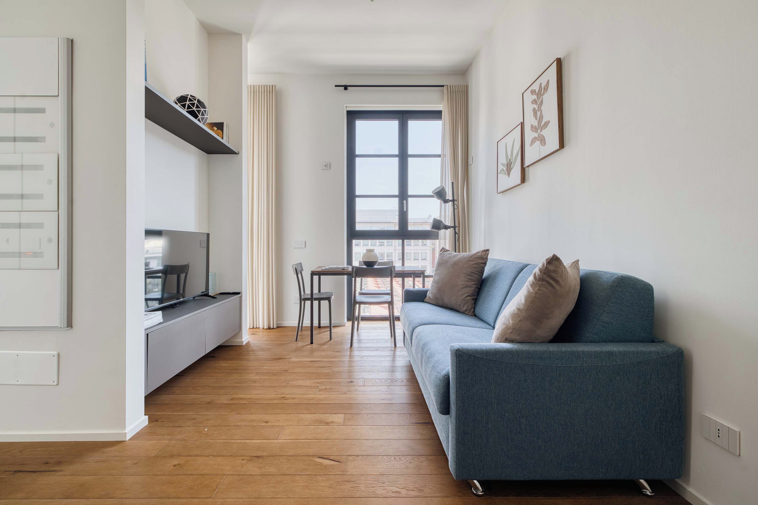 Ein zeitgemäßer Wohnraum mit Sofa, Esstisch und Fernseher.