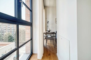 A narrow corridor with a dining area, a window with a view of buildings, and a radiator on the wall. - w* | Luxury 1BR in Milan (Milano)