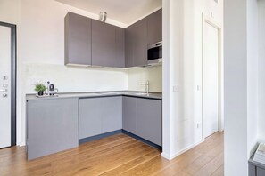 A modern kitchen with grey cabinets, a stainless steel oven, and a wooden floor. - w* | Luxury 1BR in Milan (Milano)