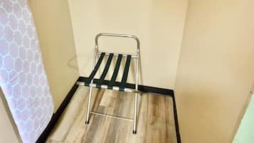 A small room with a wooden floor, a metal drying rack, and a towel hanging on the wall.