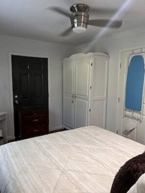 Ein Schlafzimmer mit Bett, Kleiderschrank, Tür und Deckenventilator.