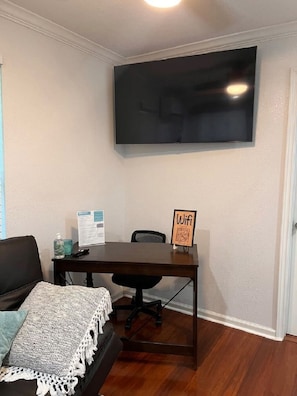 A room with a dark wooden table, a black office chair, a white wall, and a mounted flat-screen TV. - La Casita private & quiet with great location area (San Antonio)