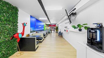 Un espacio de oficina moderno con una amplia recepción, asientos y una máquina de café.