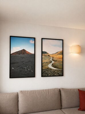 Two framed landscape photographs on a wall, a sofa, and a wall-mounted light fixture. - Villa Lava - 3-Bedroom Villa in Downtown Puerto del Carmen (Tías)